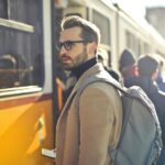 Man in Brown Coat and Gray Backpack Posing for a Photo